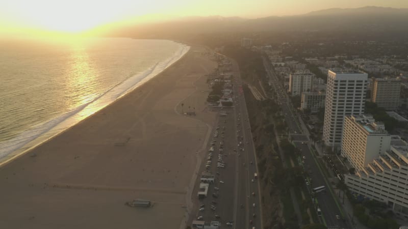 Pacific Coast Highway with light traffic and Ocean view at beautiful Golden Hour Sunset waves, Drone Establishing Shot Dolly forward