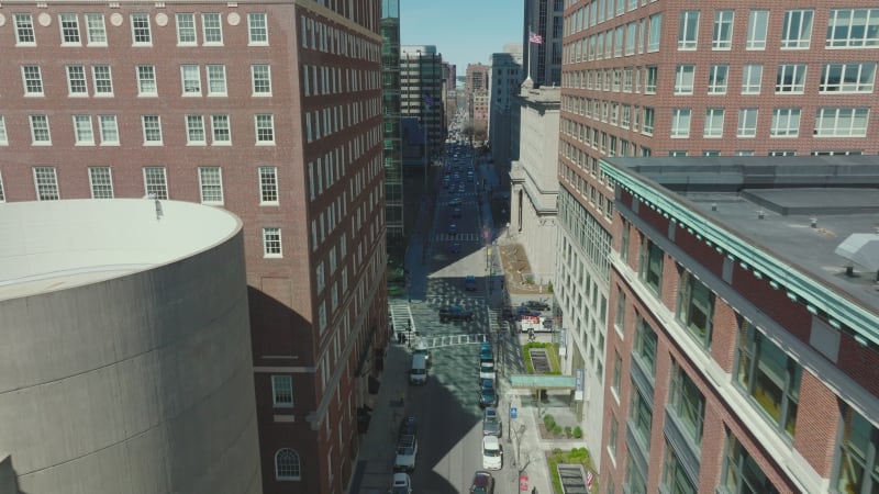 Forwards fly high above street surrounded by high rise office buildings. Sunny day in downtown. Boston, USA