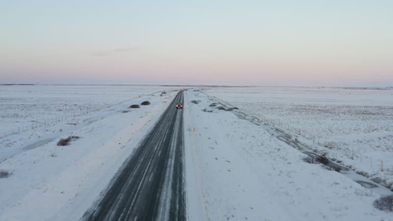 Close Up of Jeep brake lights driving on Iceland Road with Snow white Mountains and Sunset Snow, Arctic