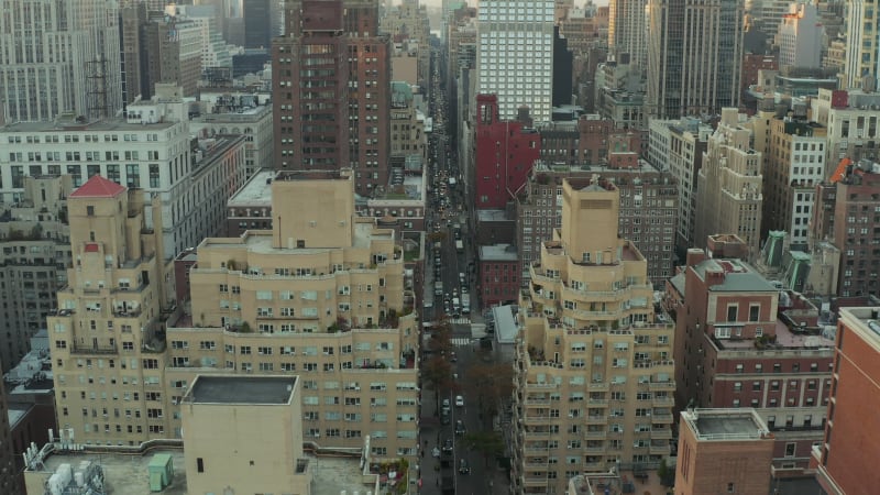 Forwards fly above long straight busy street surrounded by high rise buildings in city. Manhattan, New York City, USA