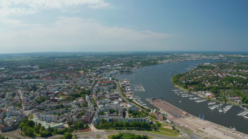 Aerial panoramic view of town on riverside of Unterwarnow river. Boats moored in marina