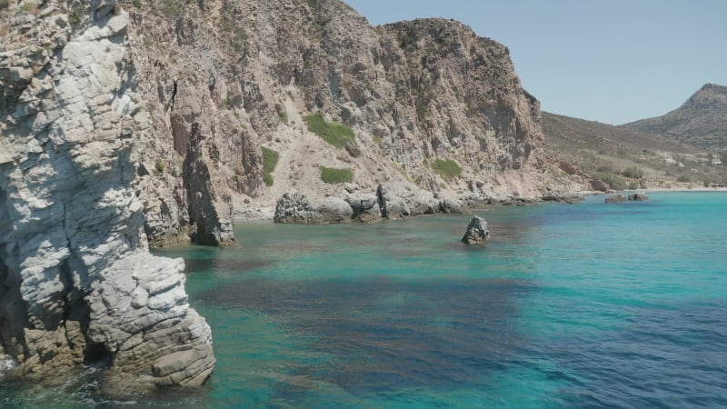 Slow Dolly Aerial in between rock formations in Turquoise Blue Ocean Water on Greek Island Milos