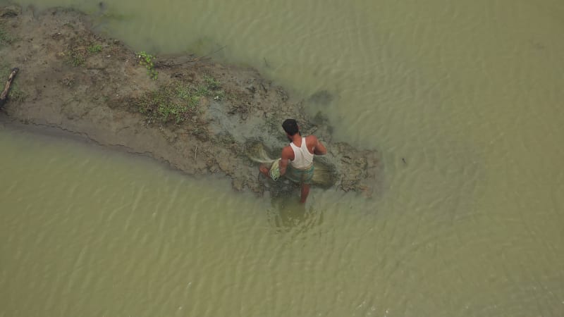 Aerial view of a person working with nets along the shoreline in Bangladesh.