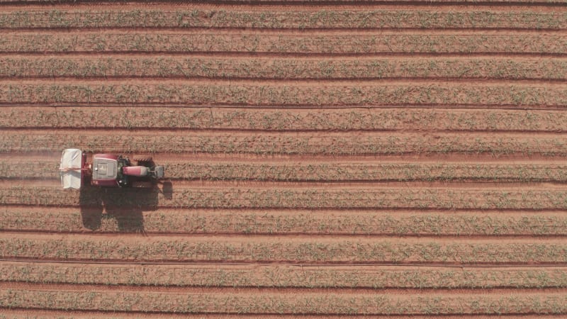 Tractor hauling a Two disc Fertilizer spreader in a large field, Aerial follow footage.