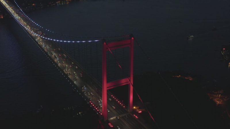 Red Bosphorus Bridge in Istanbul at Night with Car traffic into the City, Establishing Aerial backwards tilt up