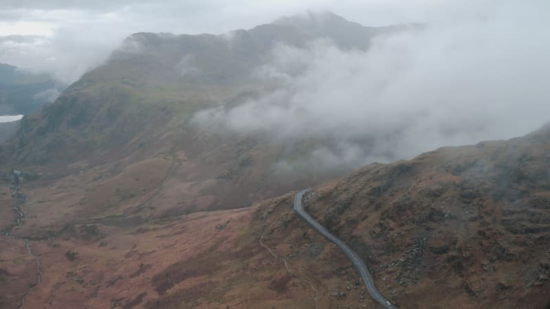 Aerial view of a river in a mountain valley surrounded by foggy mountains