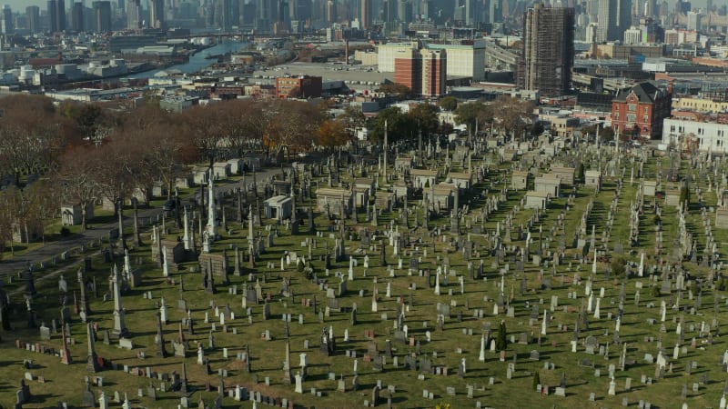 Gravestones and tombs in green grass on old Calvary Cemetery. Place of remembrance in urban neighbourhood. Queens, New York City, USA