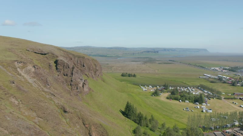 Drone view of Iceland grassy green highland countryside directly above a small town near river. Birds eye of touristic campsite near a small village in lush icelandic highland