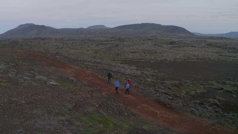 Birds eye group four people walking desert highland in Iceland enjoying spectacular panorama. Aerial view healthy hikers walking pathway exploring amazing in nature