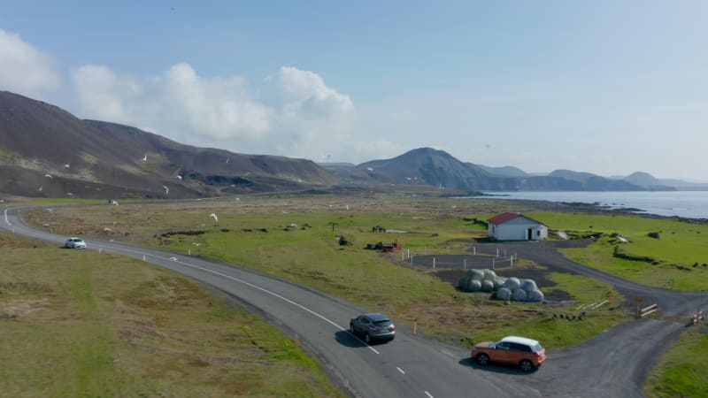 Aerial view of Ring Road, the longest and most important highway in Iceland. Drone view flight over coastline and rural house with horses