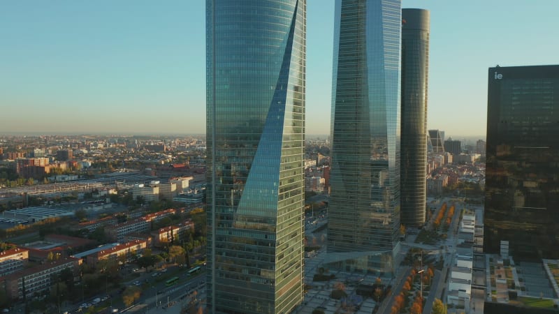 Slide and pan shot of modern glossy glass office towers in Cuatro Torres Business Area. Revealing long straight wide boulevard with traffic.