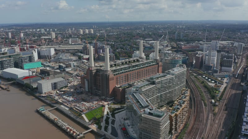 Slide and pan footage of Battersea Power Station complex. Historical coal burning power station with four chimneys on bank of Thames river. London, UK