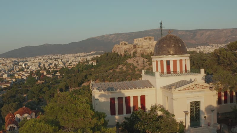 Aerial passing by National Observatory of Athens revealing Acropolis in beautiful Golden Hour