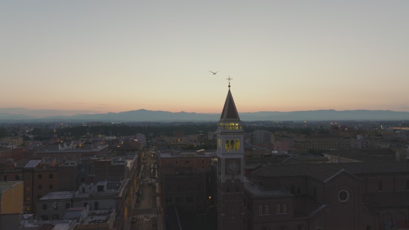 Forwards fly above buildings in historic city centre. Silhouette of old tower against colour twilight sky. Rome, Italy