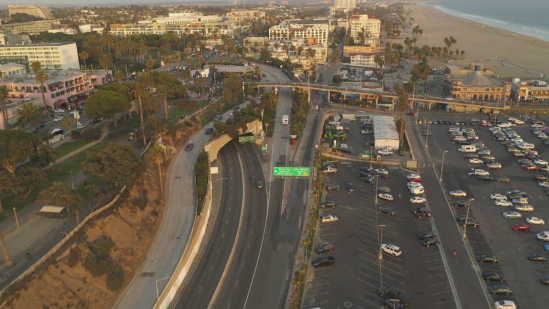 Big Parking Lot at Santa Monica Pier from above at beautiful Sunset with Tourists, tilt up revealing shot