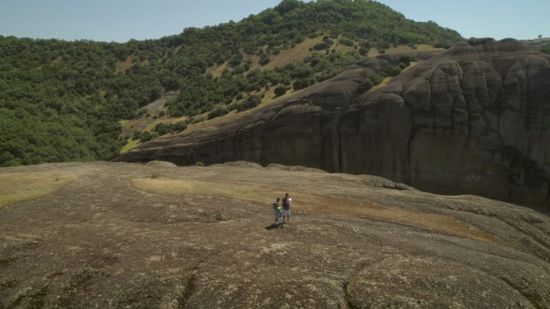 Aerial view of a couple walking near the Roussanou Monastery.