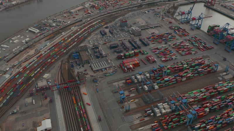 Aerial view of large cargo container terminal in Hamburg with reveal of the river and city industrial district