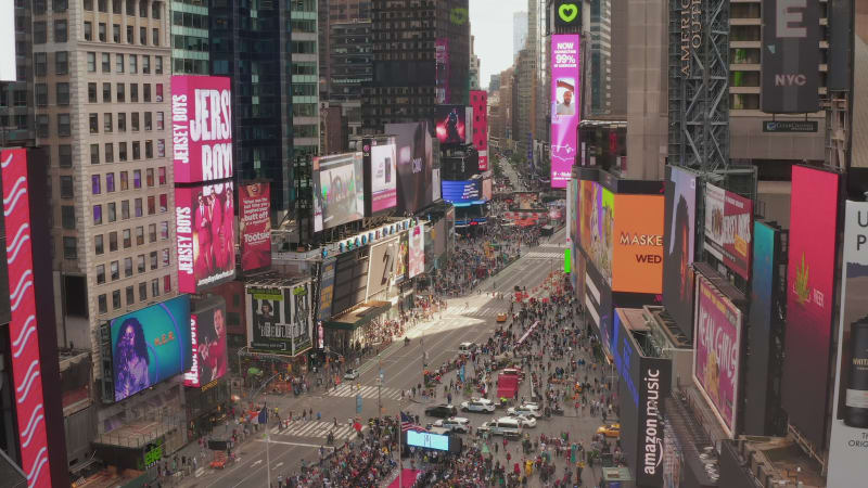 Look over Times Square heart of New York City at Daylight with crowd of people and heavy car traffic advertisements and police