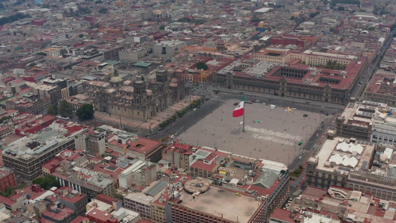 Elevated flying view of Catedral Metropolitana de la Ciudad de Mexico and Plaza de la Constitucion with huge state flag. Drone footage of historic city center. Mexico city, Mexico.