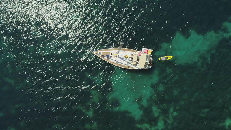 Aerial view above sailboat swinging on the coast of Varko.