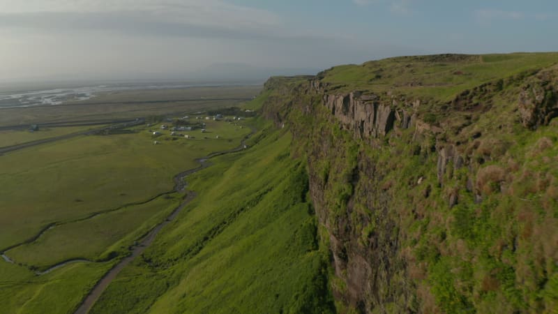 Birds eye flying toward breathtaking Seljalandsfoss waterfall, the most famous cascade in Iceland. Drone point of view of amazing icelandic landscape over mossy cliffs and majestic waterfall