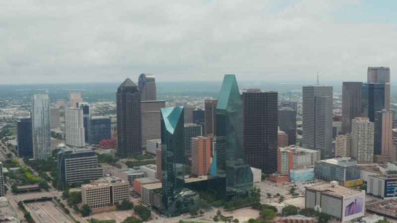 Forwards reveal of modern tall buildings at Fountain place with glass facades and irregular shape. Aerial view of downtown. Dallas, Texas, US