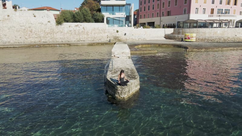 Aerial view of a woman sitting on the pier, Istria, Croatia.