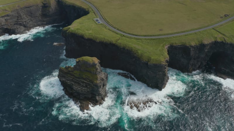 Aerial view of boiling water at coastal rocks. Amazing shot of high cliffs and green grass with road on top. Kilkee Cliff Walk, Ireland