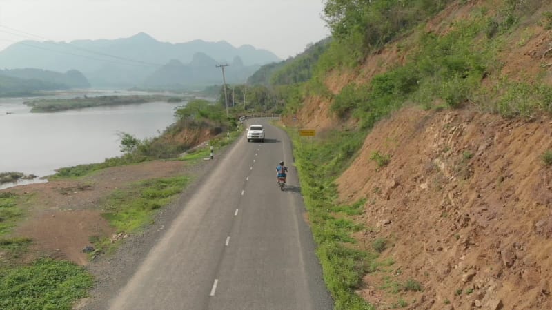 Aerial view of Motorcyclist on road next to Mekong River, Laos