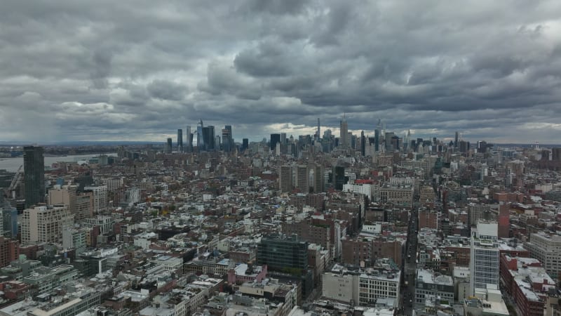 Forwards fly above town development. Aerial panoramic view of downtown skyscrapers against dramatic cloudy sky. Manhattan, New York City, USA