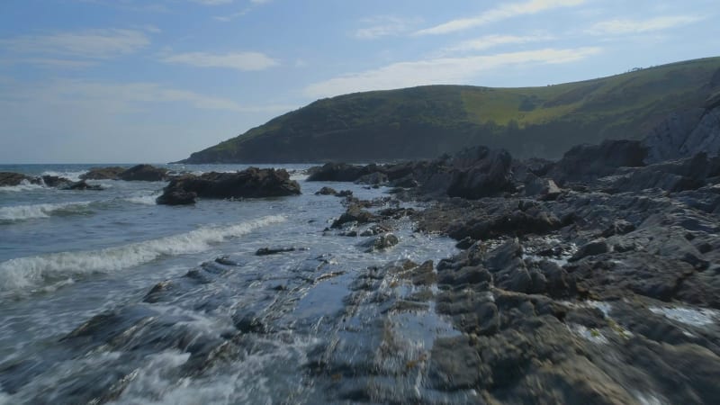 Slow Flight Over the Rugged Coastline with a Hilly Landscape