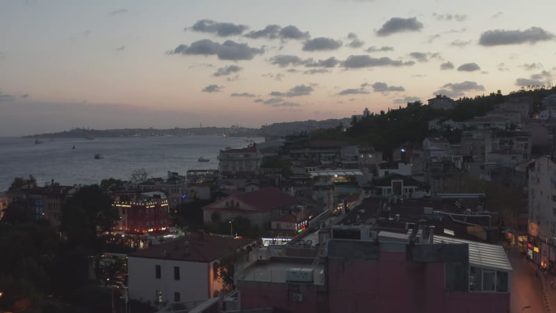 Beautiful Sunset over Istanbul Neighbourhood Ortakoy with Birds flying by and view over Bosphorus, Aerial Establishing Shot