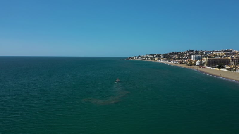 Aerial view of a small fishing boat sailing near Estepona, Malaga, Spain.