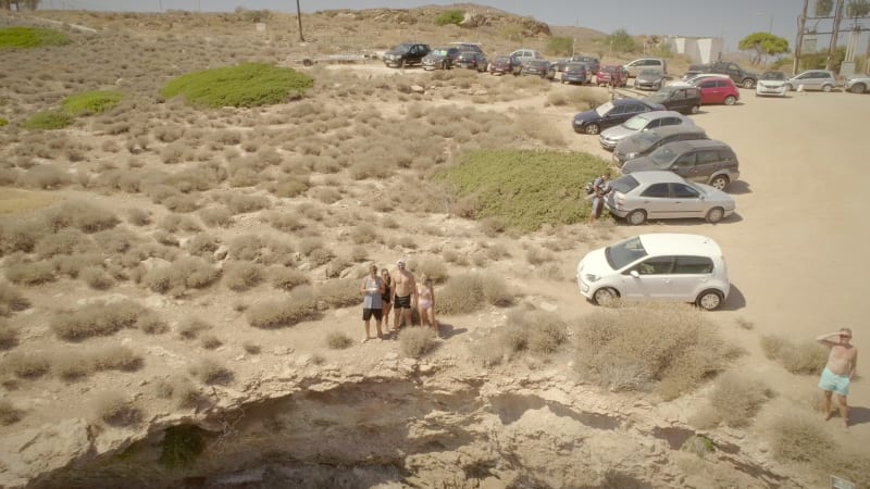 Aerial view of a group of friends standing on a small hill in front of the beach