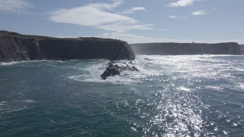 Aerial view of black cliffs in strong waves in