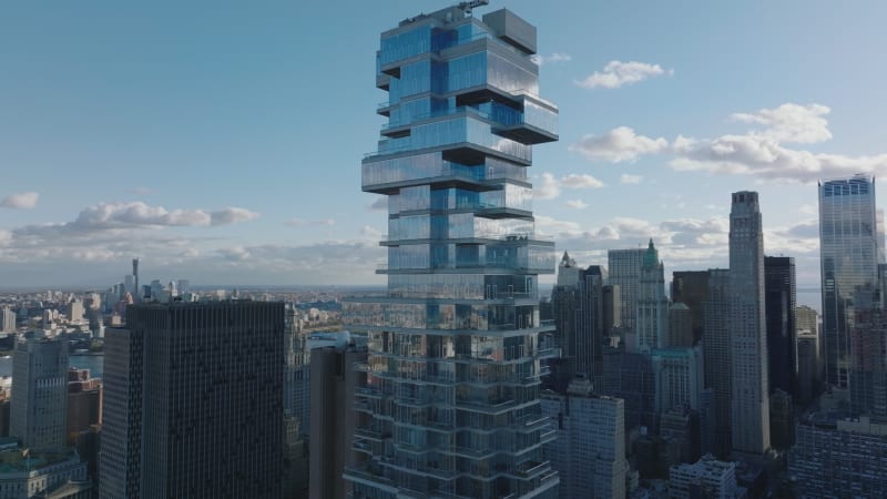 Slide and pan shot of futuristic modern designed tall office building. Jenga Tower with glass facade and terraces. Manhattan, New York City, USA