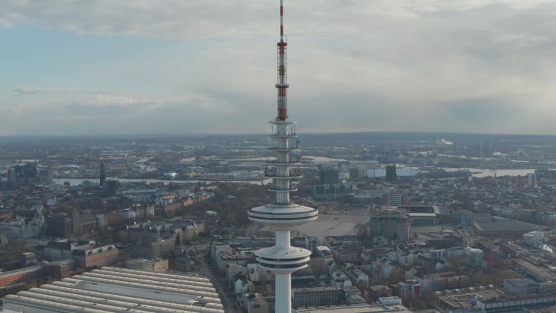 Aerial dolly out view of tall white Heinrich Hertz TV tower rising above Hamburg cityscape