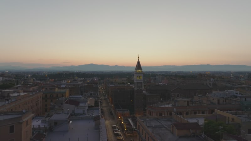 Aerial view of city at dawn. town development and historic church with tower. Silhouette of mountain ridge in distance. Rome, Italy