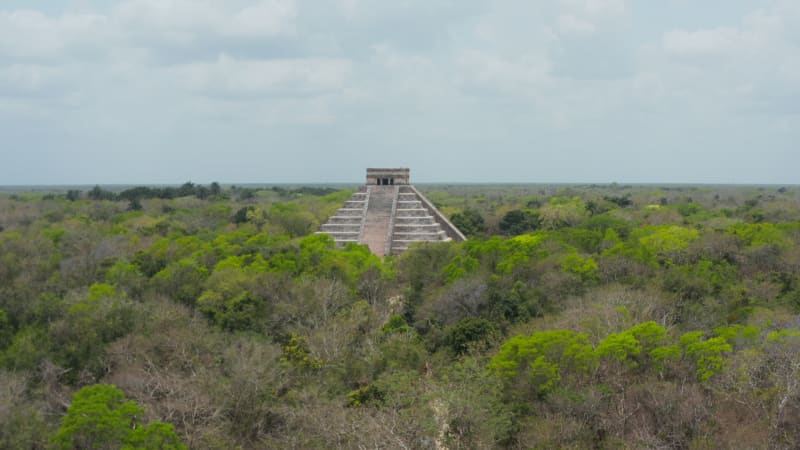 Rising up footage of remains of old Maya town surrounded by vast rain forest. Historical monuments of pre-Columbian era, Chichen Itza, Mexico.