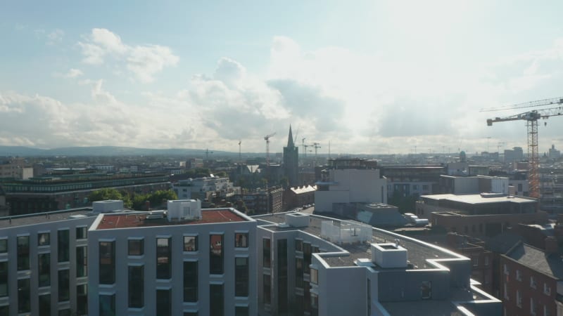 Fly over modern apartment building complex, heading towards St Patrick Cathedral tower. Dublin, Ireland