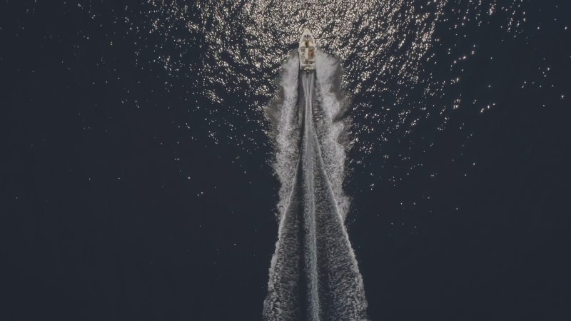 Aerial view of small speed boat with trailing wake on sea.