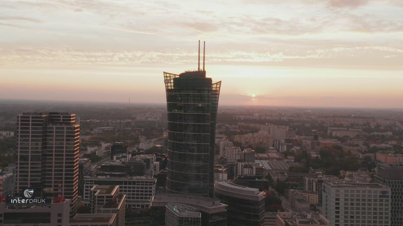 Forwards fly towards modern futuristic high rise building tower high above urban development. Warsaw, Poland