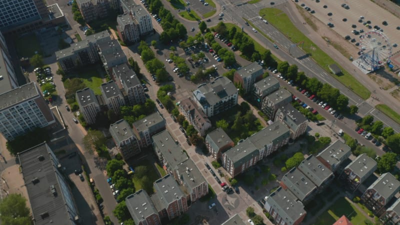 Aerial footage of housing estate, tilt up reveal of wide river and busy multi lane road leading on waterfront. High angle view of city