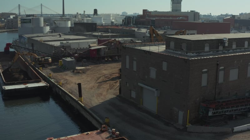 Aerial view of machinery on industrial site. Loading loose material on barge. Transporting on water. New York City, USA