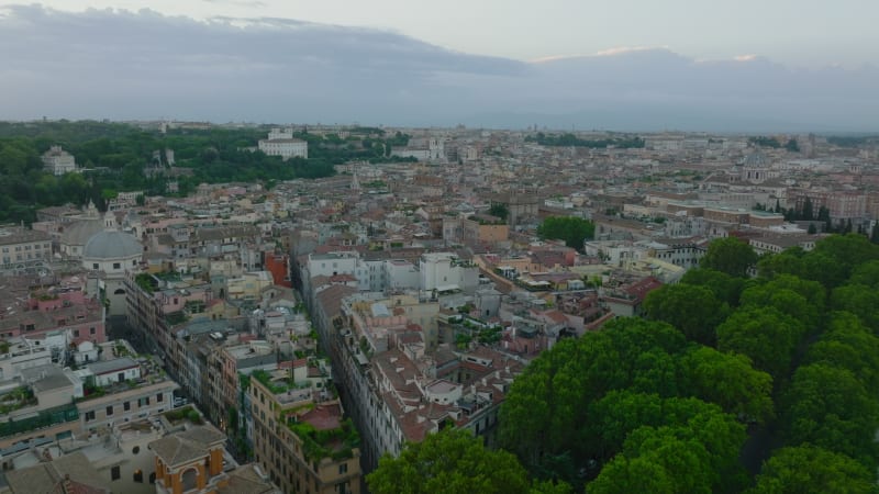 Fly above town development in historic city centre. Narrow streets and old multistorey residential buildings with rooftop terraces. Rome, Italy