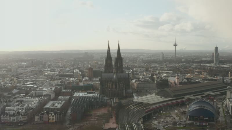 Aerial panoramic footage of large city. Train arriving to main train station next to historic gothic cathedral. Cologne, Germany