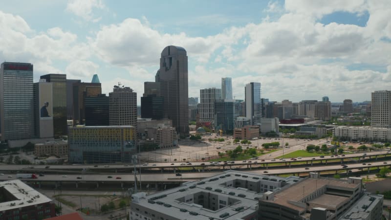Panoramic aerial view of downtown skyscrapers behind rush highway. Tall modern office building panning footage from drone. Dallas, Texas, US