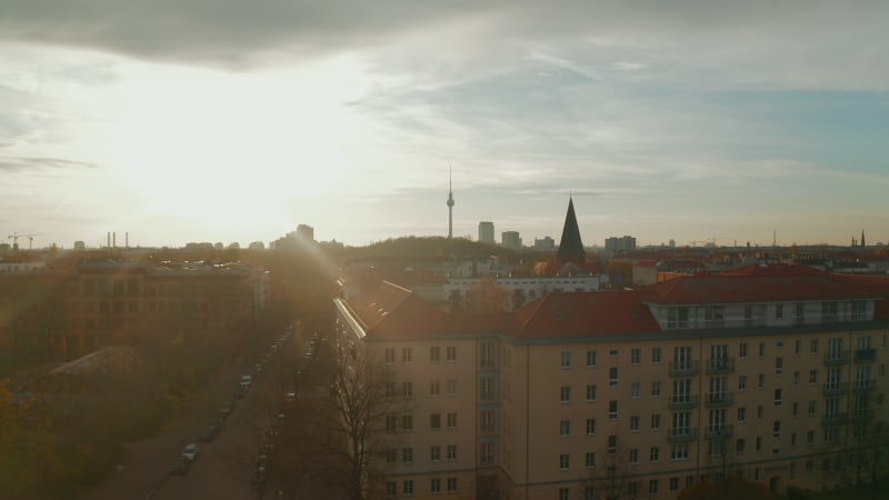 Low flight above Berlin, Germany residential neighbourhood street and rooftops towards City center with TV Tower Skyline, Scenic Autumn vibe Aerial Dolly in