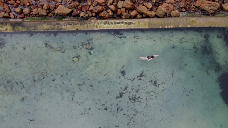 Aerial view of woman swimming in Glencairn pool, Cape Town, South Africa.