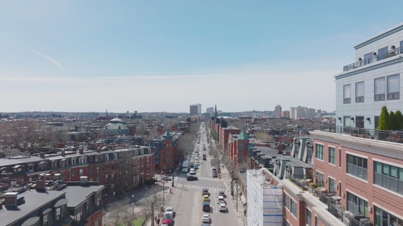 Forwards fly above street in large city. Red brick facades on townhouses along road in urban neighbourhood. Boston, USA